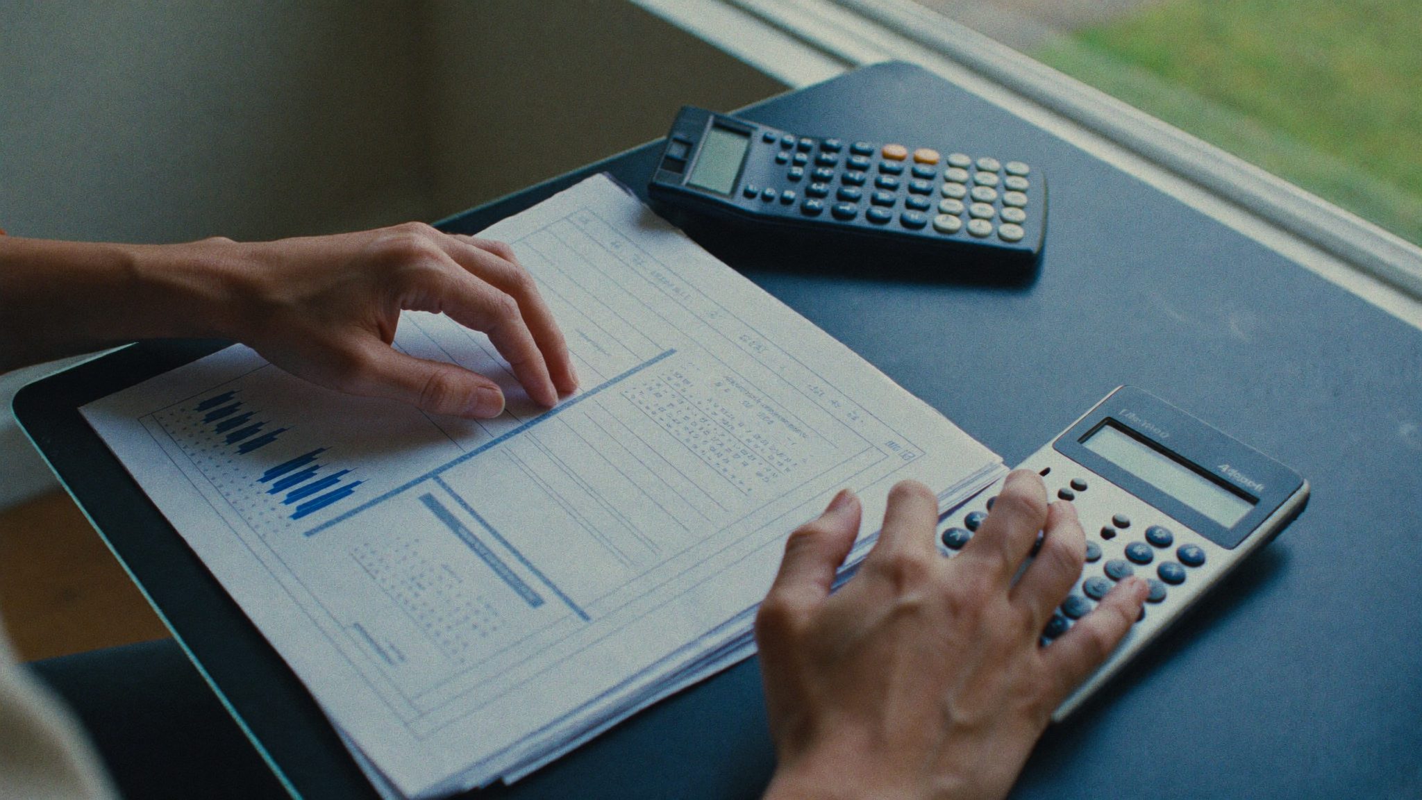 Hands working on a spreadsheet and calculator during analysis